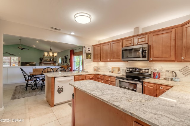 kitchen featuring pendant lighting, lofted ceiling, ceiling fan with notable chandelier, appliances with stainless steel finishes, and kitchen peninsula