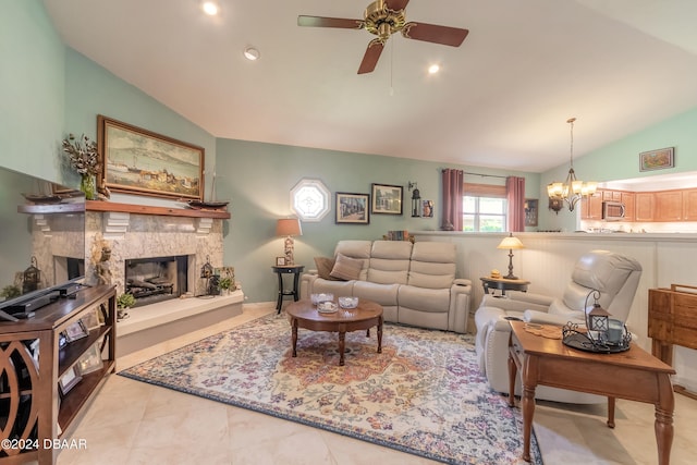 living room with ceiling fan with notable chandelier, a stone fireplace, light tile patterned floors, and vaulted ceiling