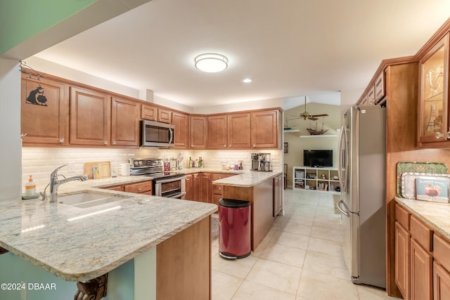 kitchen with light stone countertops, sink, kitchen peninsula, and stainless steel appliances