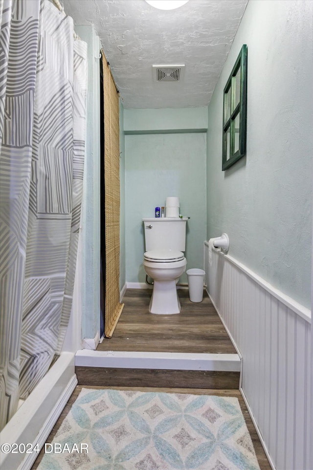 bathroom featuring wood-type flooring, toilet, and a shower with curtain