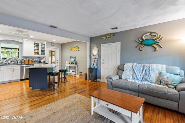 living room featuring light wood-type flooring, ceiling fan, and sink