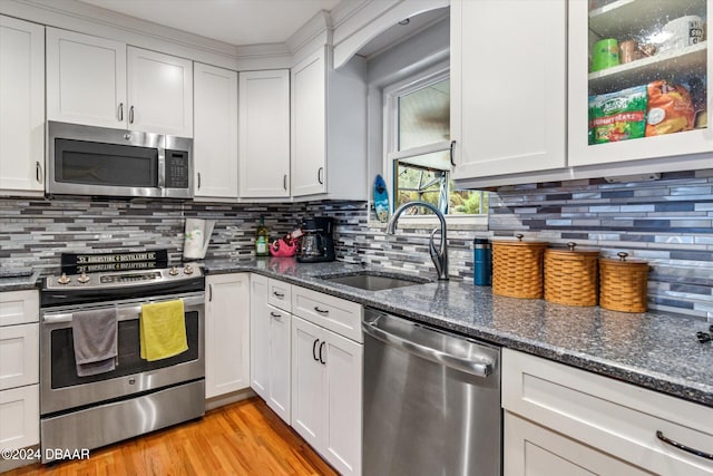 kitchen with sink, stainless steel appliances, backsplash, dark stone countertops, and white cabinets