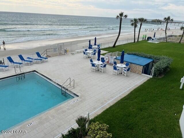 exterior space featuring a view of the beach, a water view, a patio, and a yard