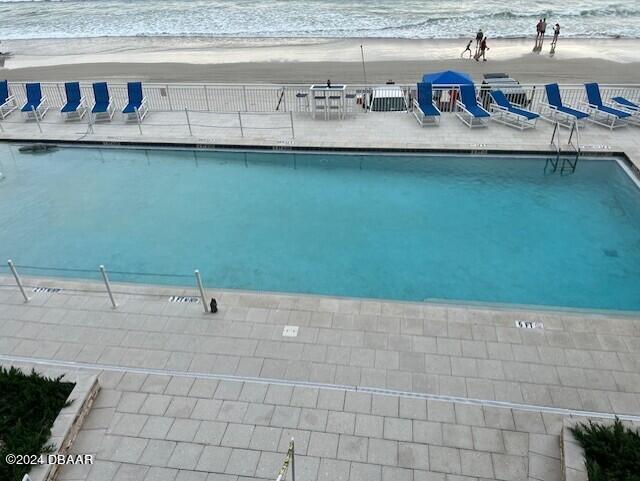 view of swimming pool featuring a view of the beach and a water view