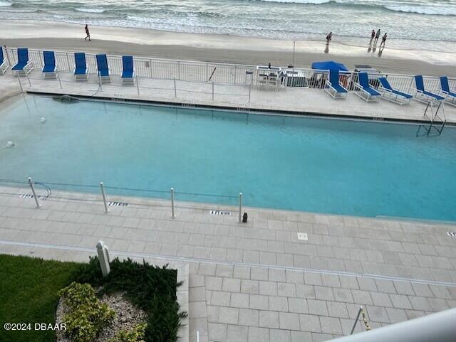 view of pool featuring a water view and a beach view