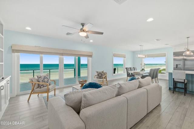 living room with light hardwood / wood-style flooring, a water view, and ceiling fan