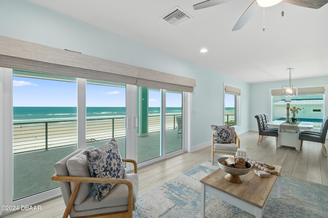 living room with light hardwood / wood-style floors, a water view, ceiling fan, and plenty of natural light