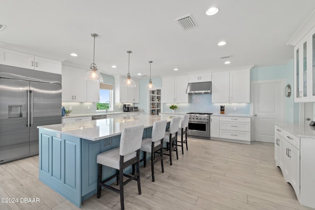 kitchen with decorative light fixtures, a large island, high quality appliances, and white cabinets