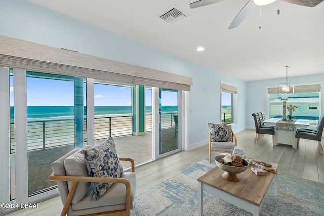 living room featuring a wealth of natural light, ceiling fan, a water view, and light hardwood / wood-style flooring