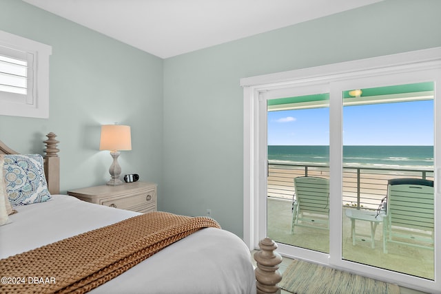 bedroom with a water view, a view of the beach, and multiple windows