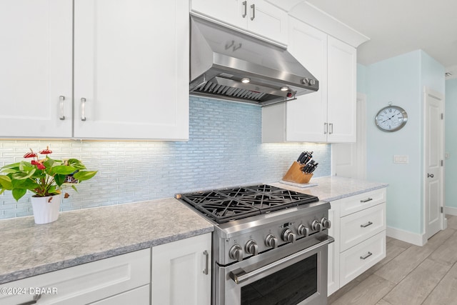 kitchen featuring white cabinets, light hardwood / wood-style floors, high end range, and tasteful backsplash