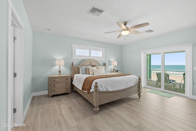 bedroom featuring light hardwood / wood-style floors, multiple windows, a water view, and access to outside