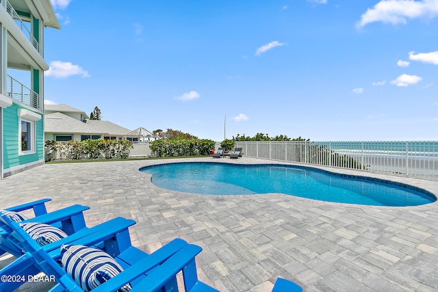 view of swimming pool featuring a patio area, a water view, and a beach view