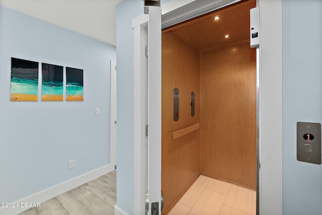 corridor featuring elevator and light hardwood / wood-style flooring