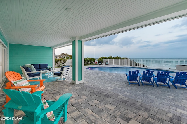 view of swimming pool with a patio, a water view, and an outdoor living space