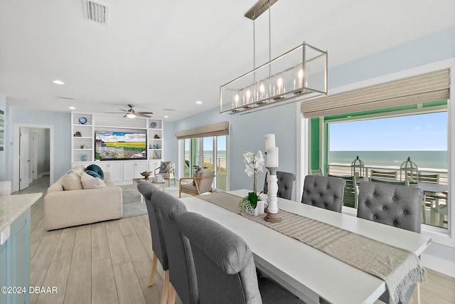 dining area with light hardwood / wood-style floors, ceiling fan with notable chandelier, and built in features