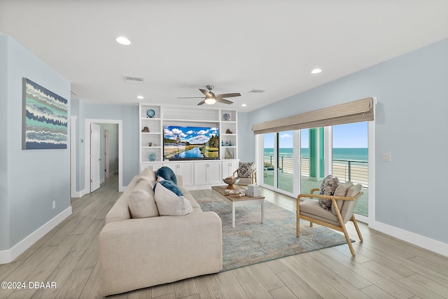 living room with built in features, ceiling fan, and light hardwood / wood-style flooring