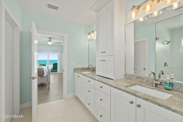 bathroom featuring walk in shower, a water view, ceiling fan, vanity, and tile patterned floors