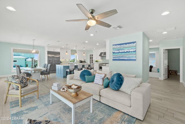 living room featuring a wealth of natural light, ceiling fan, and light hardwood / wood-style flooring