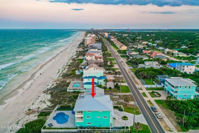 aerial view at dusk with a beach view and a water view