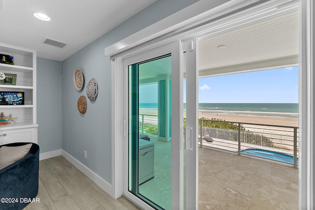 doorway to outside featuring a view of the beach, plenty of natural light, a water view, and built in features