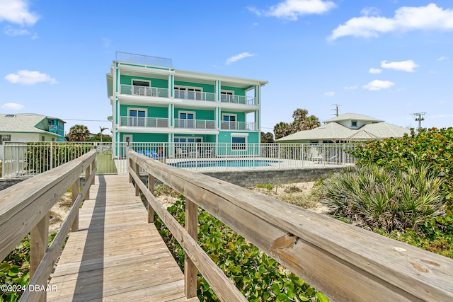 rear view of house with a balcony, a fenced in pool, and a patio area