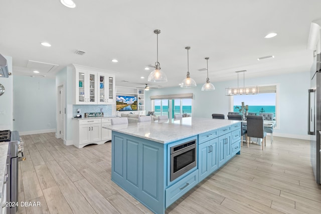 kitchen featuring decorative light fixtures, blue cabinetry, a spacious island, white cabinets, and light wood-type flooring