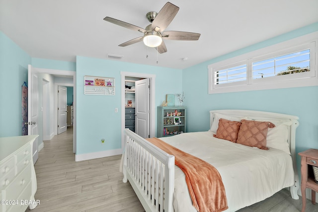 bedroom with ceiling fan, a closet, light wood-type flooring, and a walk in closet