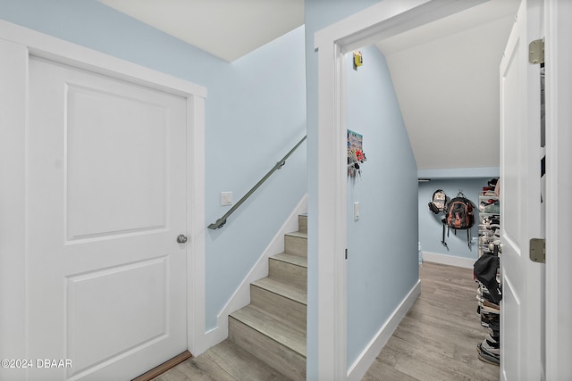 staircase with wood-type flooring and lofted ceiling