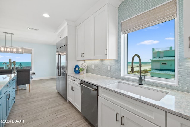 kitchen featuring white cabinetry, appliances with stainless steel finishes, pendant lighting, sink, and a water view