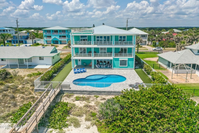 back of property with a balcony, a fenced in pool, and a patio area