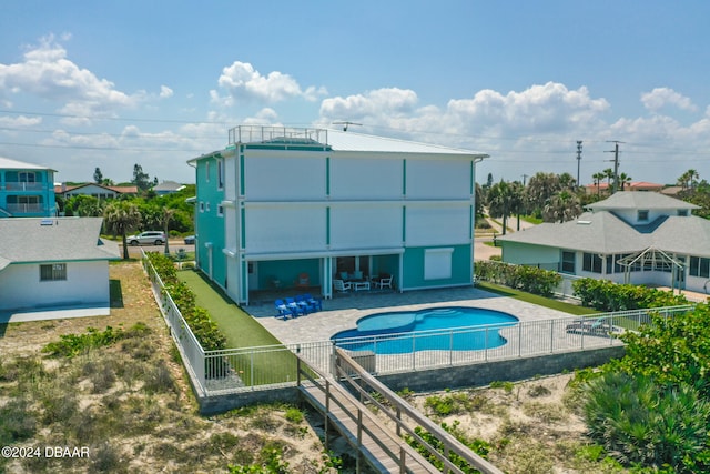 rear view of house with a fenced in pool and a patio area