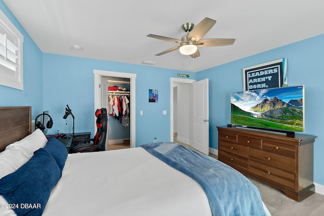 bedroom with light wood-type flooring, a spacious closet, ceiling fan, and a closet