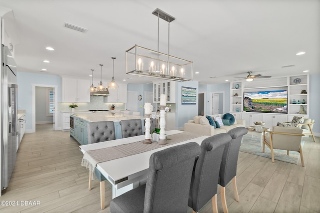 dining area with built in shelves, light wood-type flooring, and ceiling fan