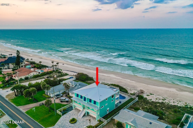 aerial view at dusk with a view of the beach and a water view