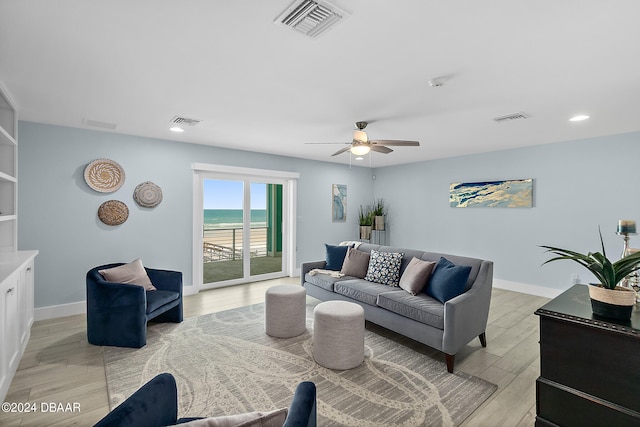 living room with light hardwood / wood-style floors, a water view, and ceiling fan