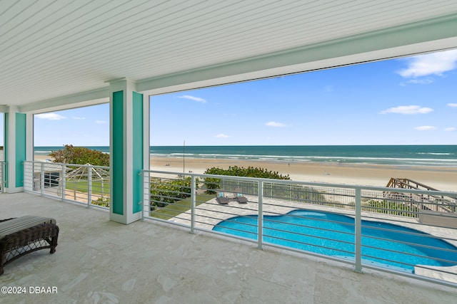 view of swimming pool with a beach view, a water view, and a patio area