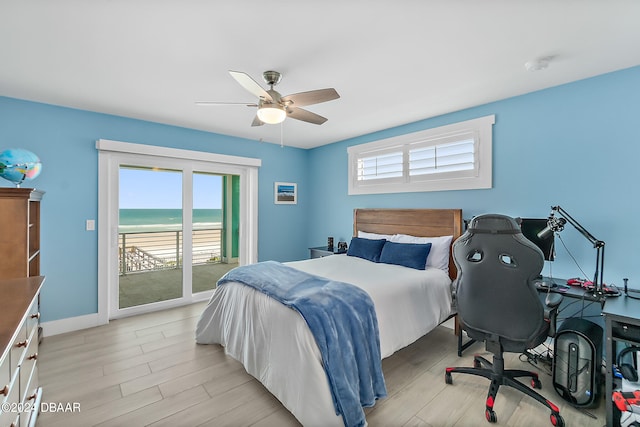 bedroom with a water view, multiple windows, ceiling fan, and access to exterior