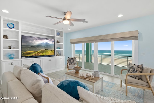 living room with ceiling fan, light wood-type flooring, and built in shelves