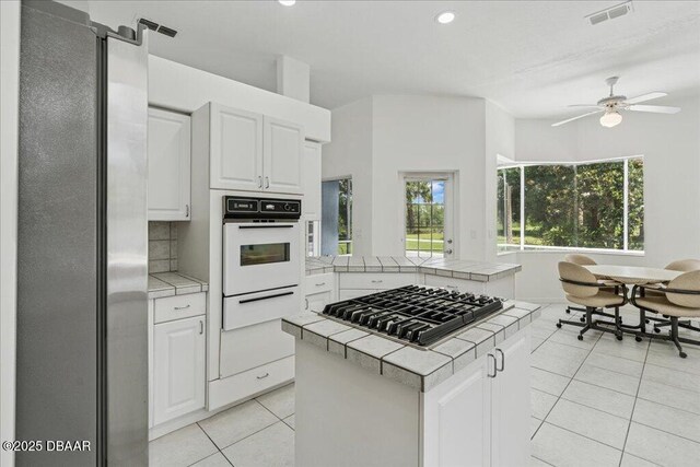 49 Ludlow Ln W W, Unit W, Palm Coast, FL 32137 - kitchen featuring tile countertops, appliances with stainless steel finishes, a warming drawer, light tile patterned floors, and a ceiling fan