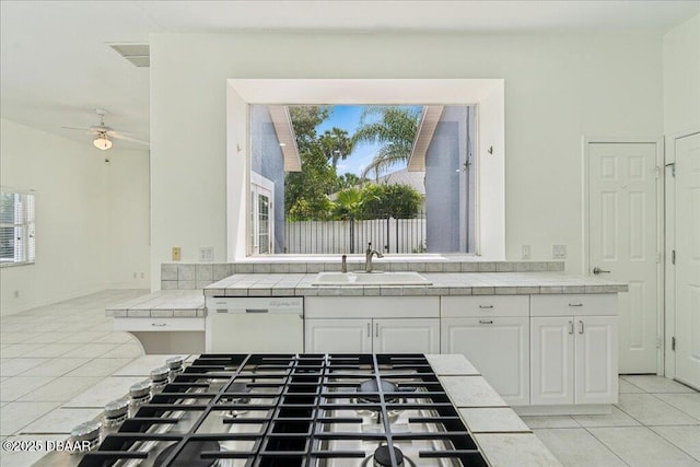49 Ludlow Ln W W, Unit W, Palm Coast, FL 32137 - kitchen with white dishwasher, tile counters, light tile patterned floors, a sink, and stainless steel gas cooktop