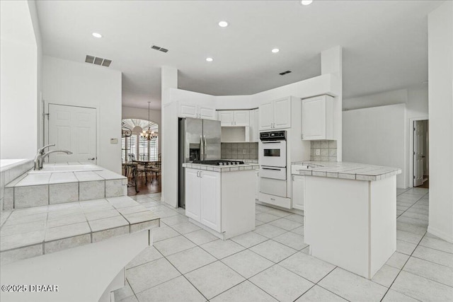 49 Ludlow Ln W W, Unit W, Palm Coast, FL 32137 - kitchen featuring oven, a peninsula, backsplash, a chandelier, and tile counters