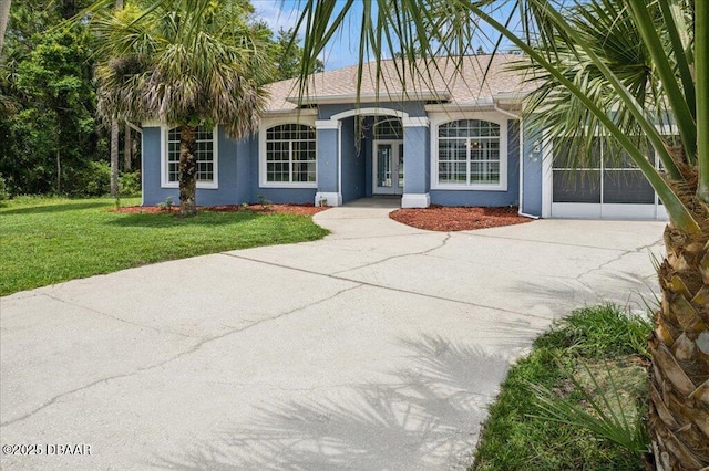 49 Ludlow Ln W W, Unit W, Palm Coast, FL 32137 - view of front facade featuring stucco siding, driveway, a front yard, and french doors