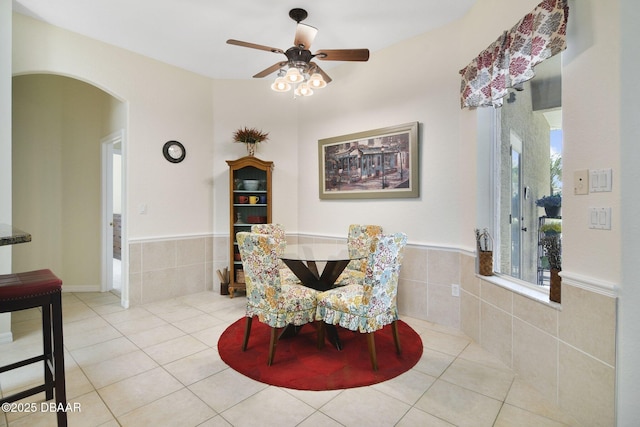 2141 Springwater Ln, Port Orange, FL 32128 - dining space with arched walkways, light tile patterned floors, wainscoting, a ceiling fan, and tile walls