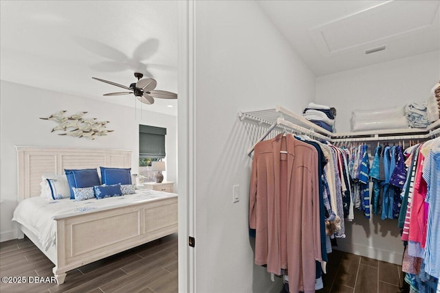 walk in closet featuring attic access, a ceiling fan, visible vents, and wood tiled floor