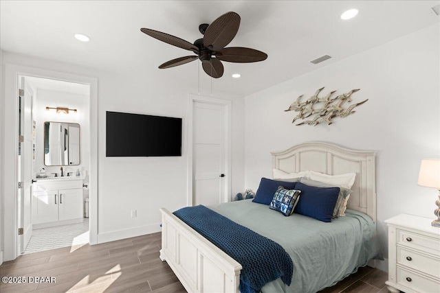 bedroom featuring dark hardwood / wood-style flooring, sink, ensuite bath, and ceiling fan