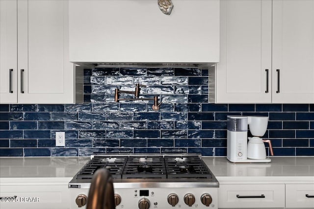 kitchen featuring backsplash, stove, and white cabinets