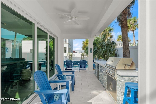 view of patio / terrace with area for grilling, exterior kitchen, ceiling fan, and fence