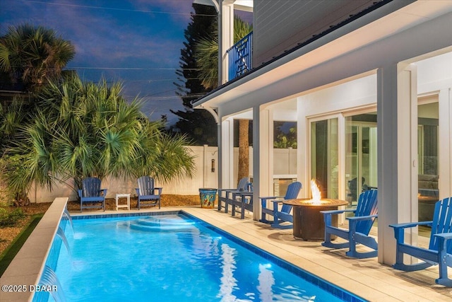 view of pool featuring a patio area, pool water feature, and an outdoor fire pit