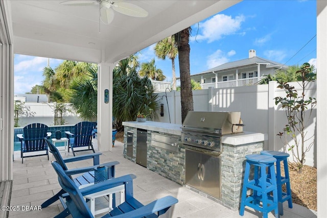 view of patio / terrace with a grill, a ceiling fan, exterior kitchen, and a fenced backyard